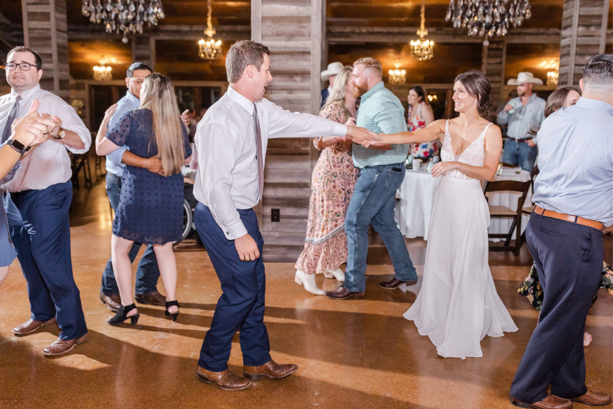 Bride and Groom dancing on the dance floor with guests during reception after wedding ceremony with Texas Wedding Ministers